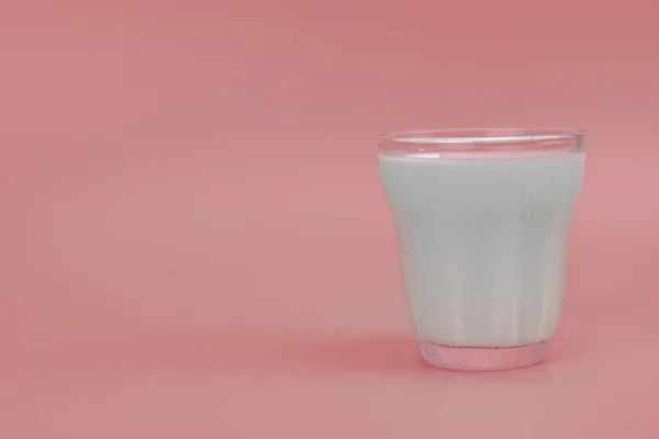 ピンクの背景にコピースペースのあるガラスの中のフレッシュミルク — ストック写真