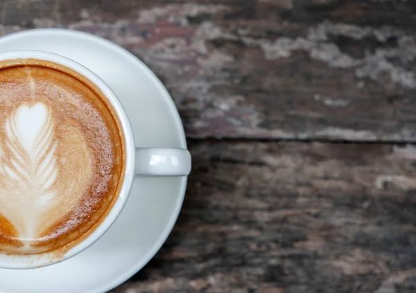 Hot coffee with late art on wooden table