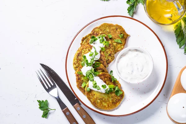 Zucchini pannkakor med gröna och gräddfil på vit. — Stockfoto