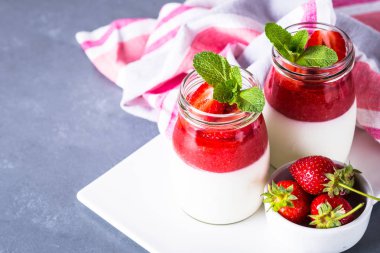 Panna cotta çilek reçeli ile. Krema çilek reçeli ve kavanozların içinde taze strawberies ile gelen tatlı tatlı.
