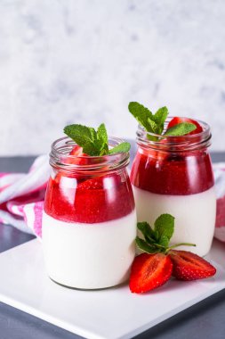 Panna cotta çilek reçeli ile. Krema çilek reçeli ve kavanozların içinde taze strawberies ile gelen tatlı tatlı.