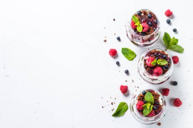 Katmanlı tatlı ekşi krema, çikolata bisküvi, reçel ve cam taze çilek. Beyaz arka plan üzerinde kopya alanı ile üstten görünüm.