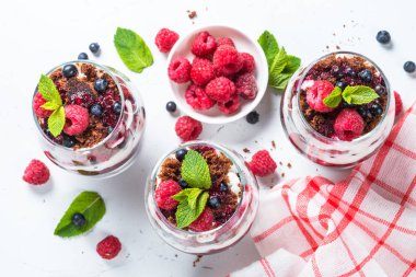 Katmanlı tatlı ekşi krema, çikolata bisküvi, reçel ve cam taze çilek. Beyaz arka plan üzerinde üstten görünüm.