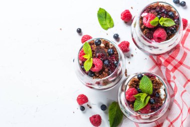 Katmanlı tatlı ekşi krema, çikolata bisküvi, reçel ve cam taze çilek. Beyaz arka plan üzerinde kopya alanı ile üstten görünüm.