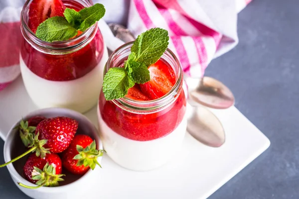 Panna cotta çilek reçeli ile. Krema çilek reçeli ve kavanozların içinde taze strawberies ile gelen tatlı tatlı.