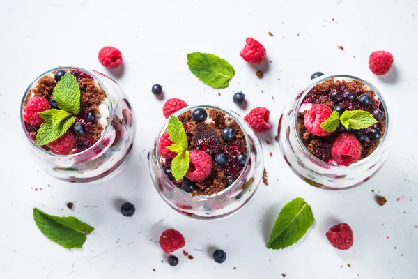 Katmanlı tatlı ekşi krema, çikolata bisküvi, reçel ve cam taze çilek. Beyaz arka plan üzerinde üstten görünüm.