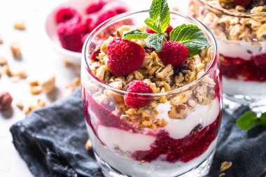 Granola, reçel ve ahududu cam kavanoza yoğurt parfafait. Yakın çekim.