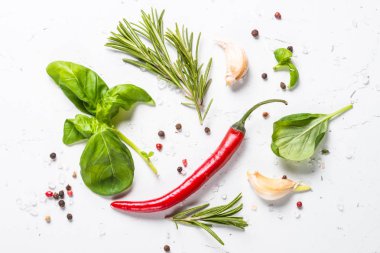 Baharat ve otlar üzerinde beyaz taş tablo. Biberiye, fesleğen, deniz tuzu, karabiber, sarımsak. Arka plan yemek yiyecek. Üstten Görünüm, kopya alanı.