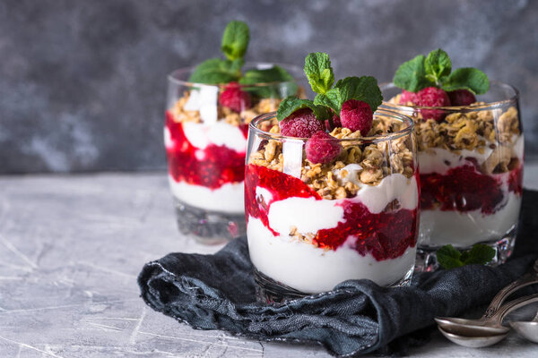 Layered dessert with yogurt, granola, jam and raspberries.