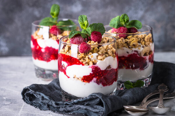 Layered dessert with yogurt, granola, jam and raspberries.