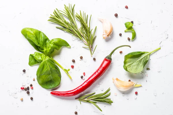 Baharat ve otlar üzerinde beyaz taş tablo. Biberiye, fesleğen, deniz tuzu, karabiber, sarımsak. Arka plan yemek yiyecek. Üstten Görünüm, kopya alanı.