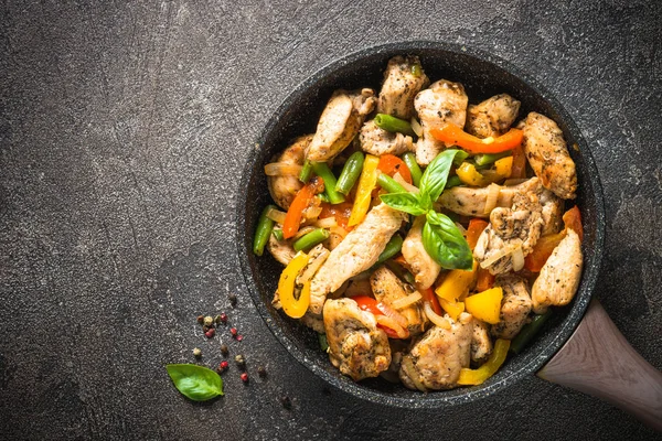 Chicken fillet fried with vegetables. Chicken stir fry. Top view on  stone table.