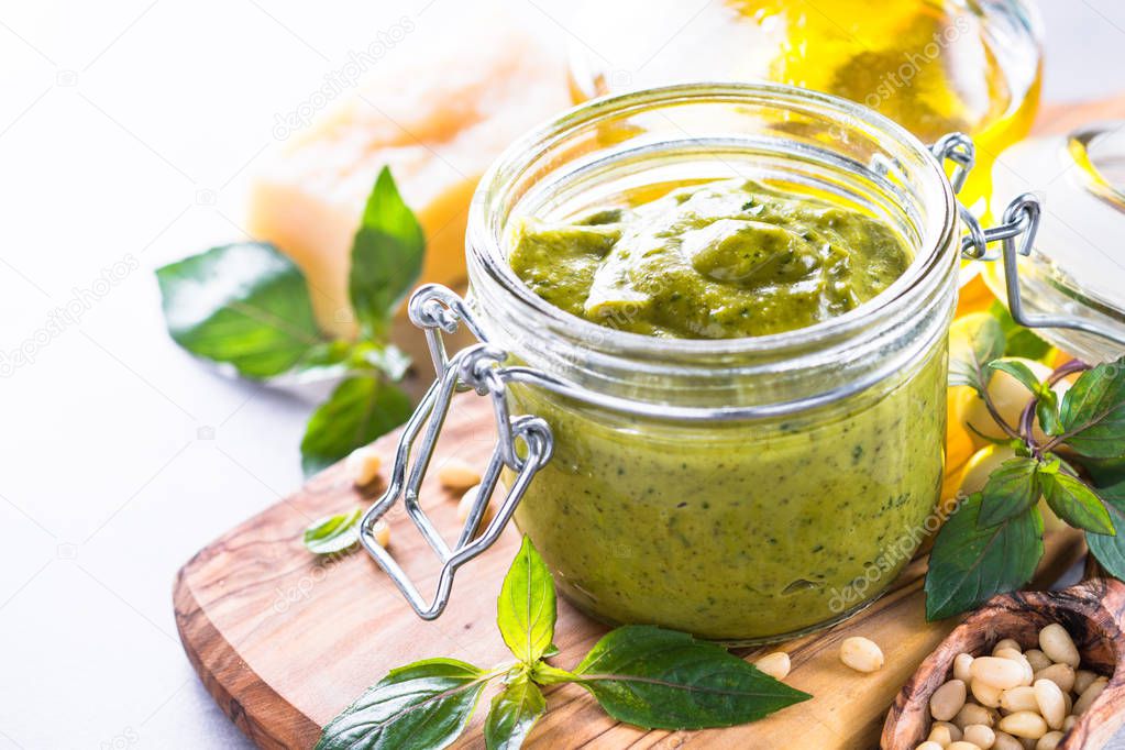Pesto sauce in glass jar and ingredients. 