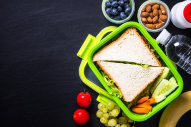 Beslenme çantası ile sandviç, sebze, muz, su, fındık ve ber