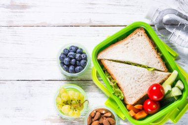 Beslenme çantası sandviç, sebze, su, fındık ve çilek ile.