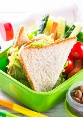 Beslenme çantası ile sandviç, sebze, muz, su, fındık ve ber