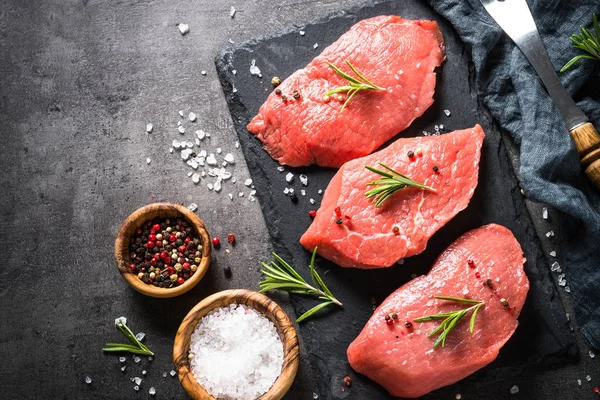 Biberiye ve baharat siyah arka plan üzerine sığır eti biftek — Stok fotoğraf
