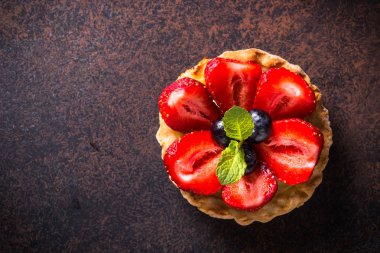 Çilekli tart karanlık masada. Üstten görünüm.