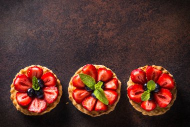 Çilekli tart karanlık masada. Üstten görünüm.