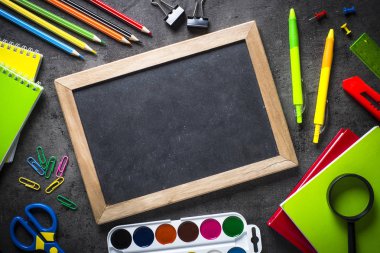 Siyah arka plan üzerine yazı tahtası ile okul ve ofis malzemeleri. 