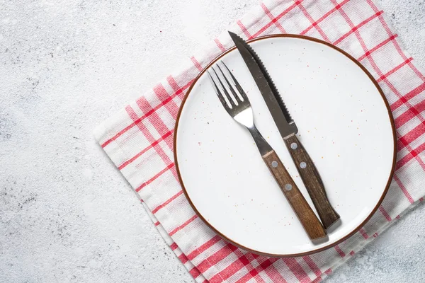White plate, cutlery and napkin on stone table top view. — Stock Photo, Image