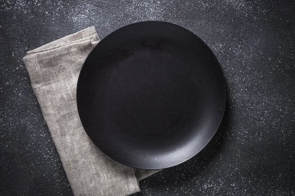 石のテーブルの上の黒いプレート、カトラリー、ナプキン. — ストック写真