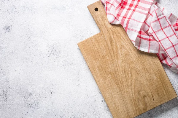 Empty wooden cutting board and tablecloth on white stone table. — Stock Photo, Image