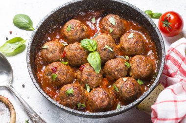 Beyaz masa üzerinde domates soslu köfte.