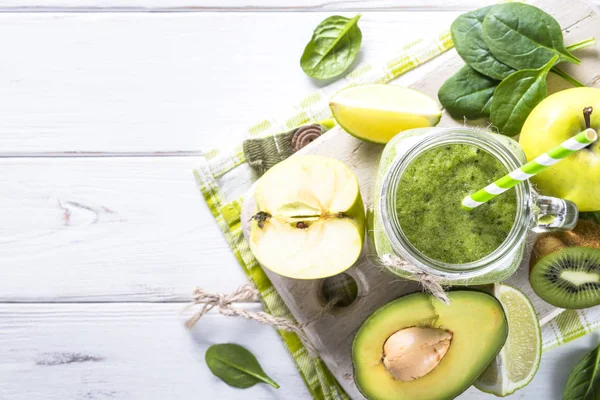 Green smoothie and ingredients on white wooden table. — Stock Photo, Image