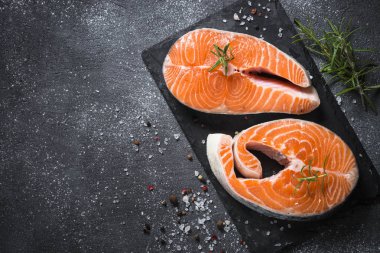 Somon bifteği çiğ balık pişirmeye hazır. Siyah tahta üzerinde üst görünüm.