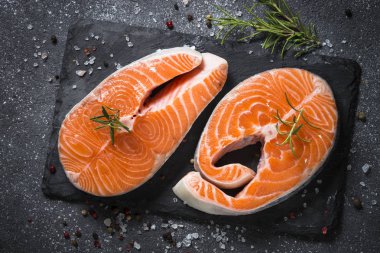 Somon bifteği çiğ balık pişirmeye hazır. Siyah tahta üzerinde üst görünüm.