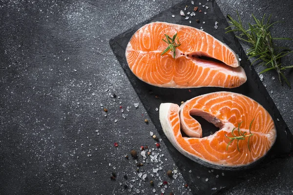 Somon bifteği çiğ balık pişirmeye hazır. Siyah tahta üzerinde üst görünüm.