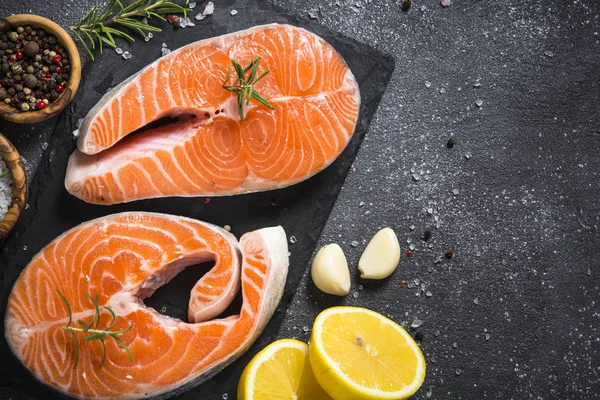 Somon bifteği çiğ balık pişirmeye hazır. Siyah tahta üzerinde üst görünüm.