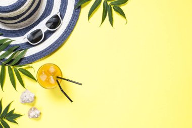 Yaz seyahat tatil kavramı. Çizgili şapka, içki, güneş gözlüğü ve sarı zemin üzerine tropikal yaprak. Kopya alanı ile üstten görünüm.