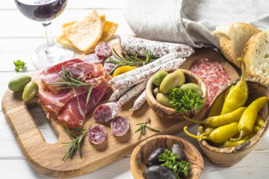 Meze - eti, jambon, salam, zeytin ve kırmızı şarap Beyaz ahşap masanın üzerine dilimlenmiş.