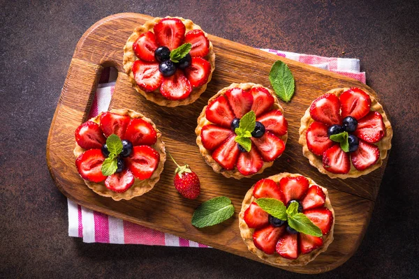 Çilek muhallebi krem tart ve taze meyveleri koyu paslı masada. Üstten görünüm.