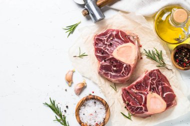 Taze çiğ Dana biftek osso bucco baharatlar ile. Mermer et. Beyaz masa üzerinde kopya alanı ile üstten görünüm.