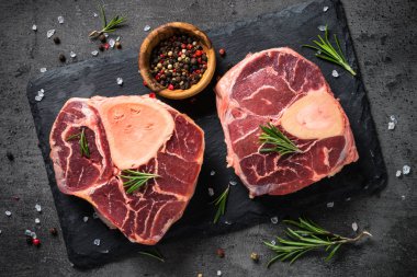 Ham sığır eti biftek osso bucco baharatlar ile siyah taş tabloda. Mermer et. Üstten görünüm.