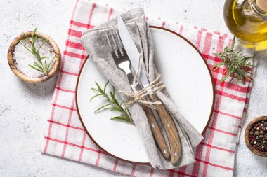 Beyaz tabak ve çatal bıçak takımı taş masa üstü görünümü. 