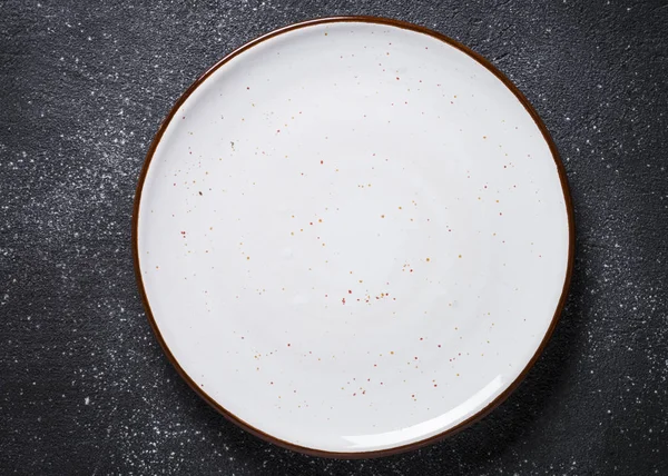 Empty white plate on dark stone table top view. — Stock Photo, Image