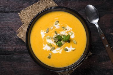 Koyu ahşap masa üzerinde kabak kremalı çorba.