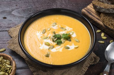 Koyu ahşap masa üzerinde kabak kremalı çorba.