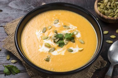 Koyu ahşap masa üzerinde kabak kremalı çorba.