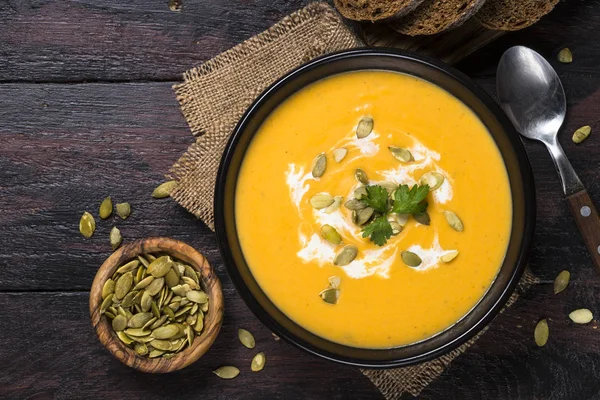 Pumpkin cream soup on dark wooden table. — Stock Photo, Image