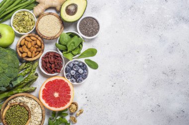 Superfoods ışık taş zemin üzerine. Organik Gıda ve sağlıklı vegan gıda. Baklagiller, fındık, tohum, avokado ve yeşil bezelye, kuşkonmaz. Üstten görünüm kopya alanı.