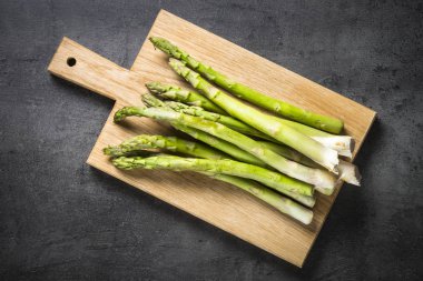 Siyah arduvaz arka plan üzerine taze yeşil kuşkonmaz.