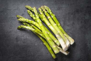 Siyah arduvaz arka plan üzerine taze yeşil kuşkonmaz.