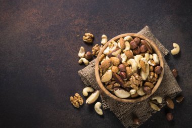 Karanlık taş masada ahşap kase fındık ürün yelpazesine. Kaju fıstığı, fındık, ceviz, badem, Brezilya fındık ve çam fıstığı. Kopya alanı ile üstten görünüm.