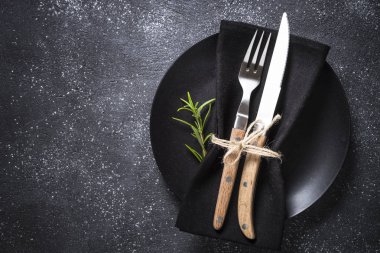 Siyah tabak, çatal bıçak ve peçete..