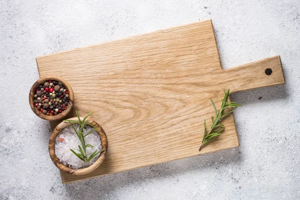 Planche à découper en bois avec sel de mer et poivre sur languette en pierre blanche — Photo